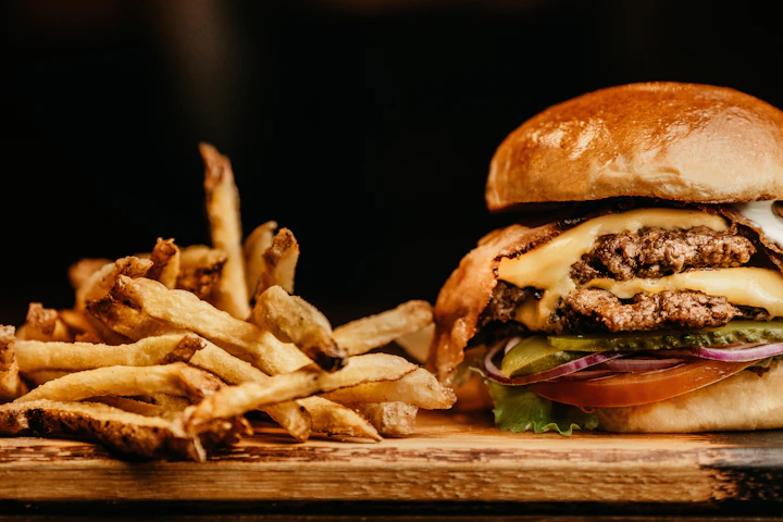 A double cheeseburger next to a pile of fries